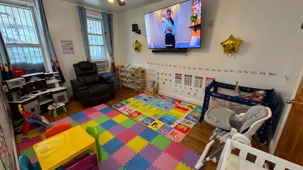 Vista amplia del salón principal con el área de juegos, TV, corralito y sillita alta