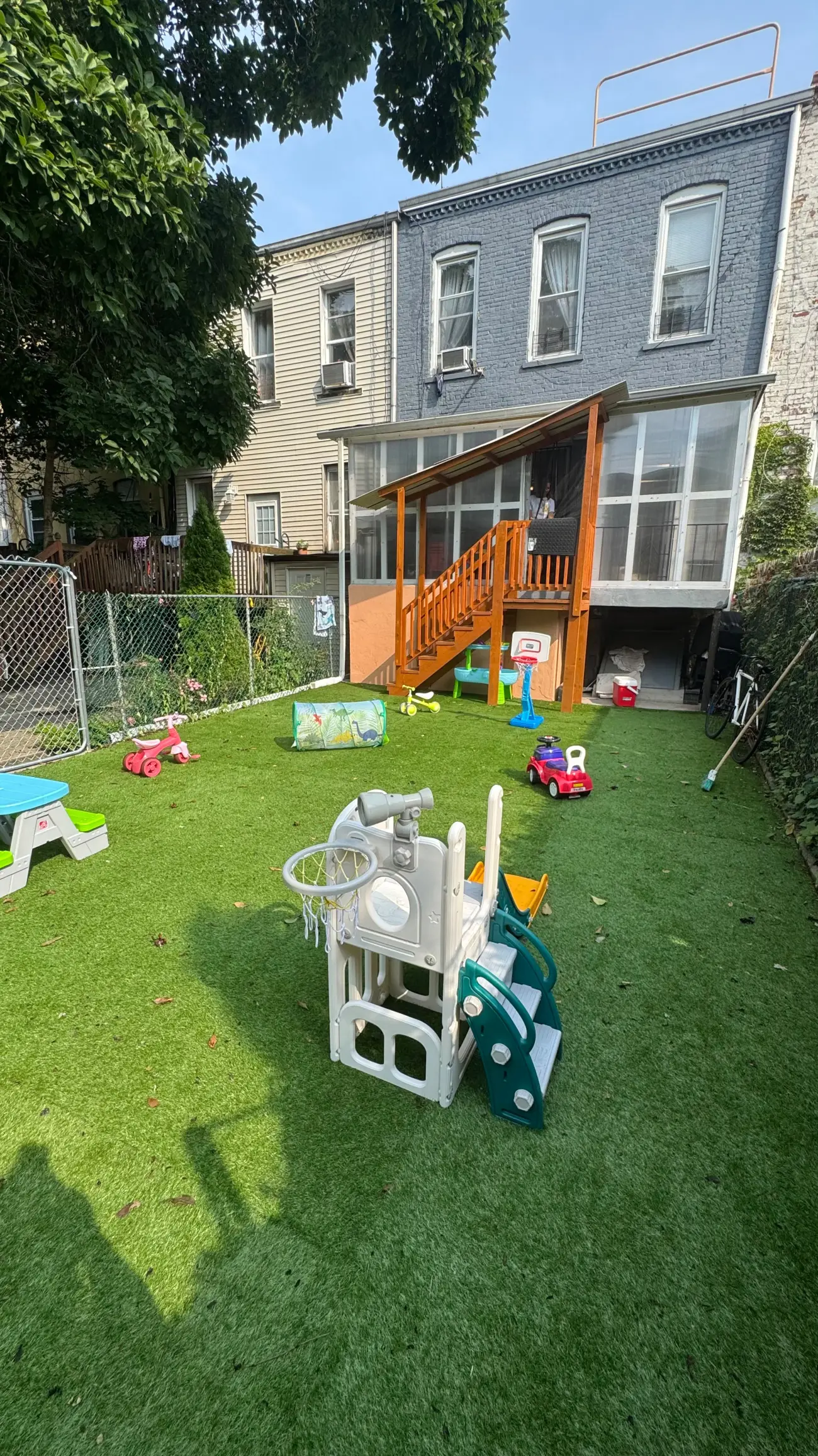 La casa vista desde el patio trasero, con el porche de madera y el área de juegos infantiles